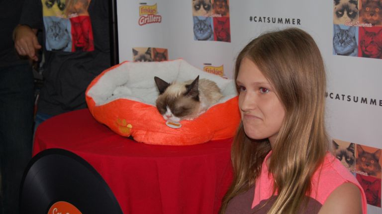 A fan poses with Grumpy Cat at the 