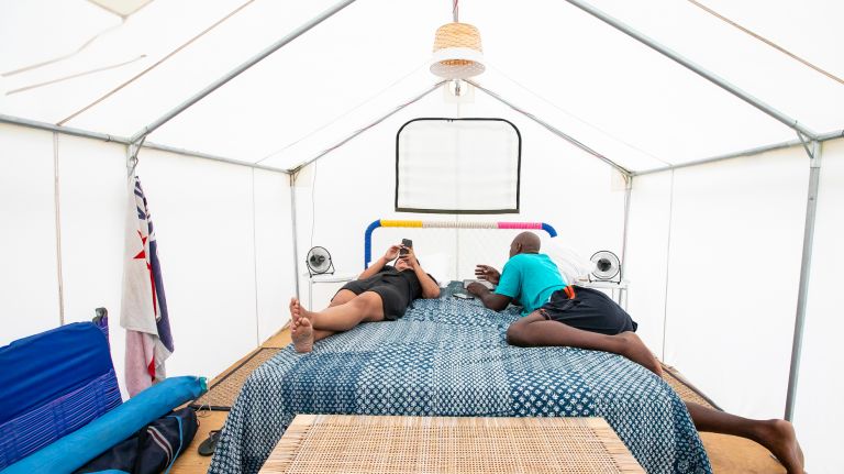 Xiomara Luna and Jedi Tention of the Bronx relax in their Camp Rockaway tent, underneath a solar-powered ceiling fan and atop a queen-size bed.