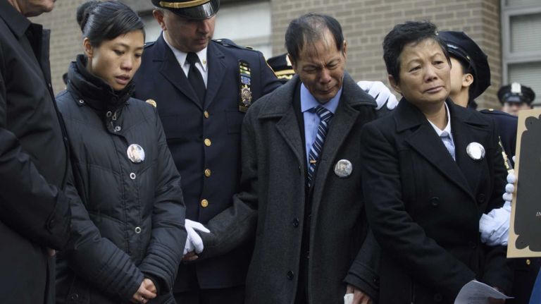 Pei Xia Chen, second from left, the widow NYPD Detective Wei Tang Liu, and his parents Wei Tang Liu, second from right and Xiu Yan Li, right, attend a memorial plaque dedication ceremony honoring Detective Liu and Detective Rafael Ramos at the 84th Precinct in Brooklyn on Sunday, Dec. 20, 2015. Liu and Ramos were shot and while in a squad car last December.