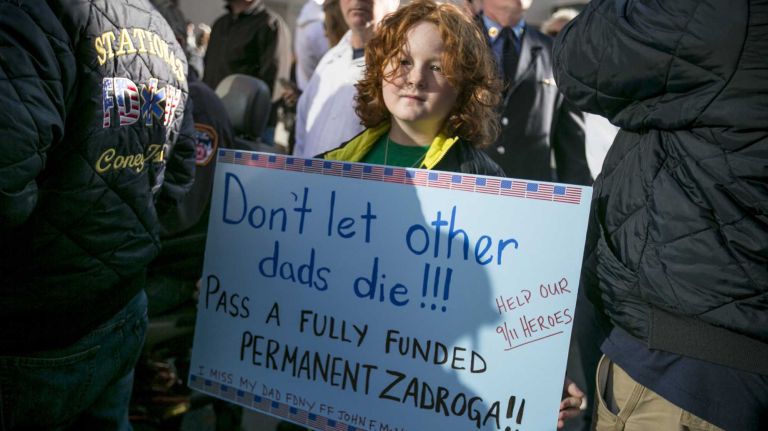 Jack McNamara, 9, whose father, FDNY firefighter John McNamara, died  of 9/11-related cancer in 2009, holds up a sign at a press conference calling for the permanent funding of the Zadroga 9/11 Health and Compensation Act, at Silverstein Family Park, on Sunday, Dec. 6, 2015.