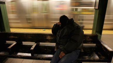 A homeless man sleeps as a Q train passes on Dec. 20, 2005.