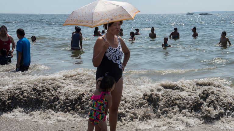 People try to shade themselves from the heat the beach on Coney Island on Labor Day, Sept. 7, 2015. 