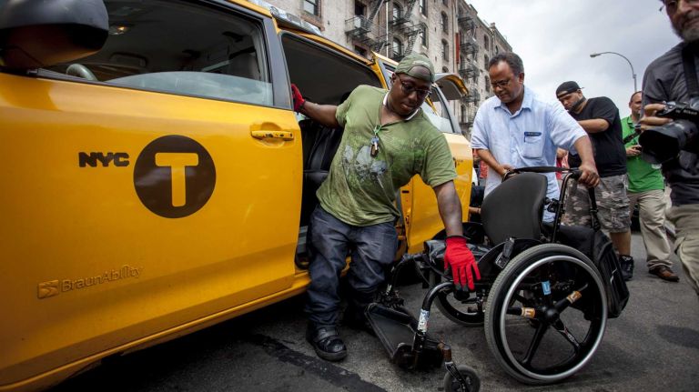 Dustin Jones of Bronx, 27, a disability advocate who sits on the board of Disabled In Action, gets of a yellow cap to join the Taxis For All Campaign protest outside Uber's New York City headquarters in Manhattan on Thursday, July 30, 2015.