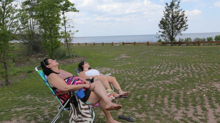 Gina Gallo, left, and Wendy Rabiner relax on the grass in Wolfe's Pond Park in Prince's Bay, Staten Island, Friday, May 22, 2015.