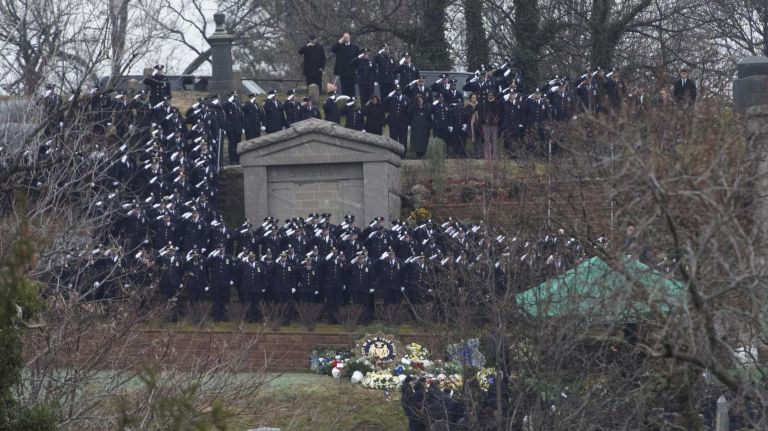 NYPD officers salute as Wenjian Liu is buried at Cypress Hills Cemetery in Brooklyn on Sunday, Jan. 4, 2015. 