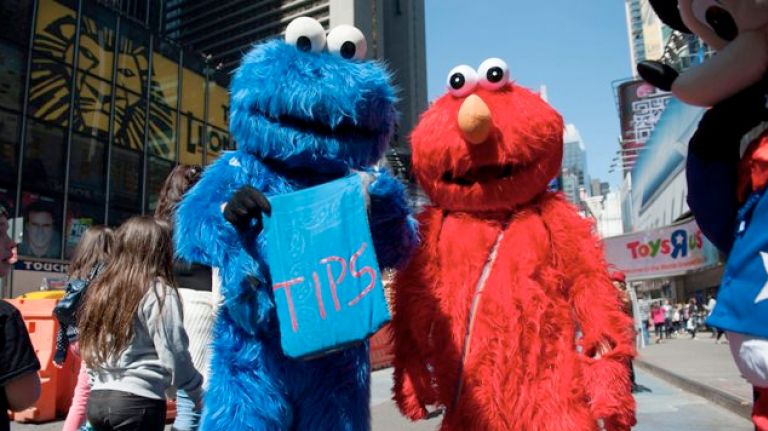 People dressed as the Cookie Monster and Elmo work in Times Square.