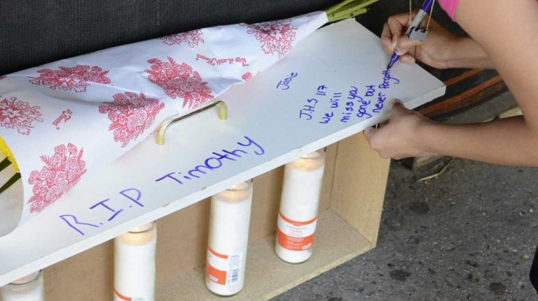 A student sets up a memorial in front of IS 117 in the Bronx where fellow student Timothy Crump, 14, was fatally stabbed, allegedly by another student, after school let out June 18, 2014.