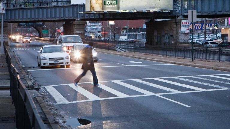 A pedistrian crosses Queens Boulevard as traffic moves along in Rego Park. (Dec. 15, 2013)