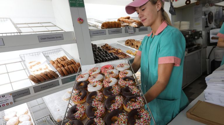 An employee with a tray of frosted doughnuts at Peter Pan Donut Shop on Sept. 19.