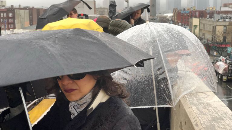 Commuters at the 46th Street 7 train station wait in the rain on Thursday morning.