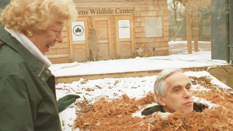 Henry Stern predicts an early spring after poking his head through a manmade burrow as Queens Borough President Claire Shulman looks on in 1996. &nbsp;