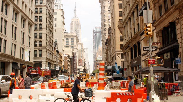 Pedestrians and cyclists make their way through barricades on East 20th Street and Fifth Avenue after a steam pipe explosion on July 19 upended the lives of businesses and residents in the Flatiron district. 