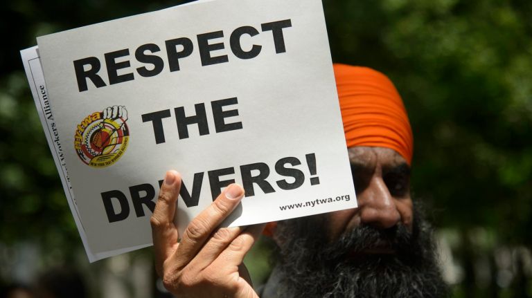 Taxi driver Rajinder Singh demonstrates during a rally outside City Hall Tuesday calling on the city to address the financial crisis facing drivers.