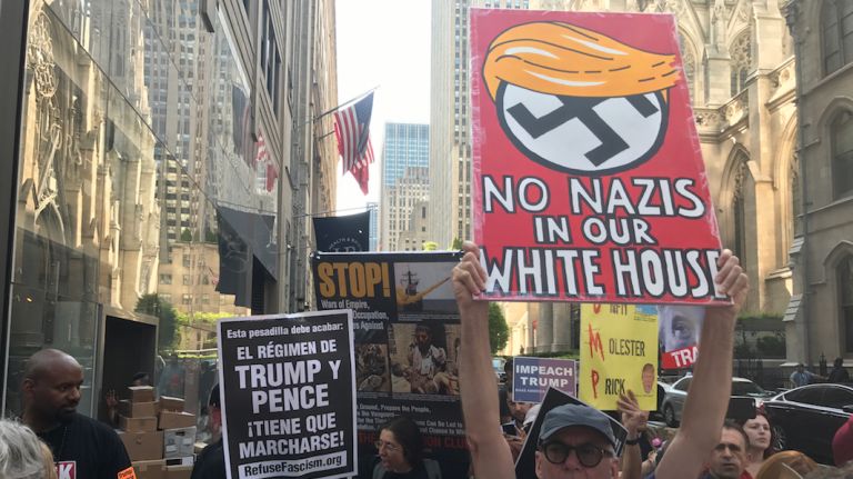 Protesters hold signs on 50th Street and Fifth Avenue as President Donald Trump attends a fundraising dinner at the nearby Lotte New York Palace Hotel in midtown.