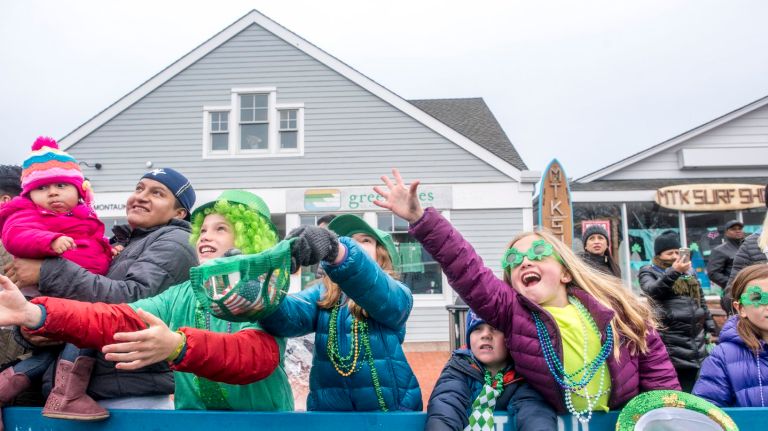Revelers reach for candy and bead necklaces thrown from passing floats during Montauk's annual St. Patrick's Day Parade, March, 26, 2017.
