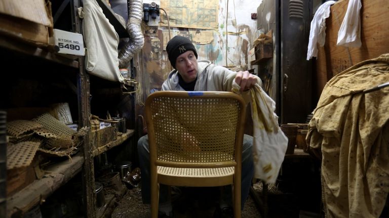 Sean Bausert, whose family started the business in 1899, stains a chair.