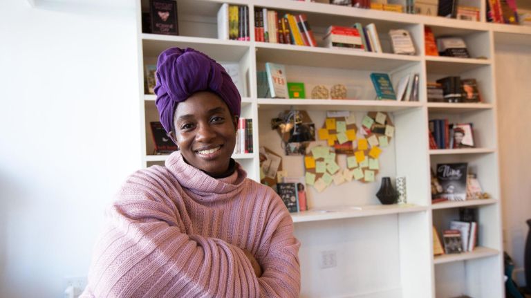 Kalima DeSuze, owner of Cafe con Libros, a feminist bookstore in Crown Heights, Brooklyn, with a selection of books behind her, Friday, Jan. 26, 2018.