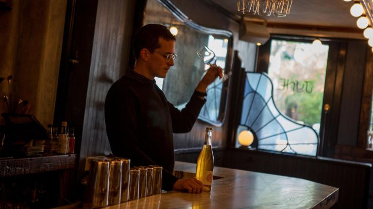 Nick Tilly, the general manager of June, gets ready to open a bottle of wine at the bar.