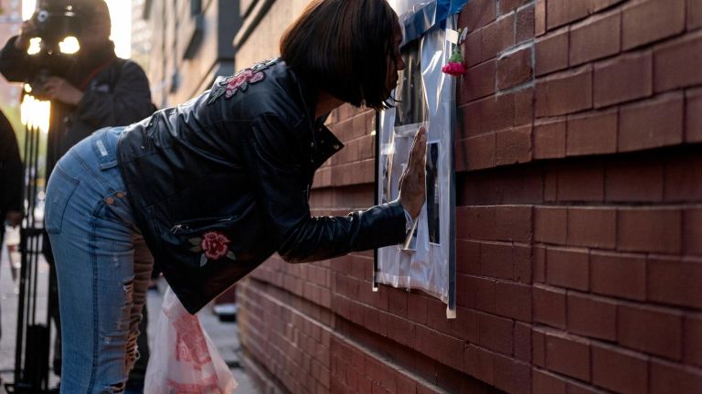 A mourner kisses a sign during a candlelight vigil Wednesday in honor of the six family members who died in a fire in Harlem.