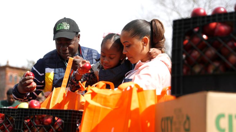 Tracy Morgan packages apples with his wife, Megan Wollover and daughter, Maven Sonae Morgan at the new Hattie Carthan Community Garden in Brooklyn.