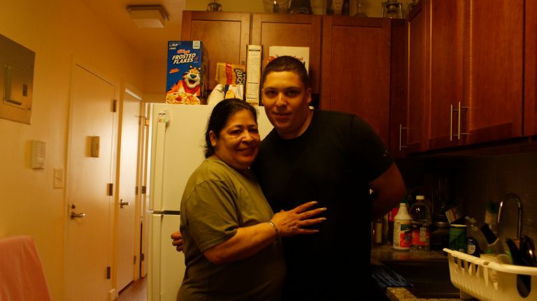 Nancy Bonaparte, 58, poses Thursday with son Luis Lopez, 23, next to her newly renovated kitchen cabinets in an affordable housing building that was recently renovated as a $9.4 million preservation project in Bedford-Stuyvesant.
