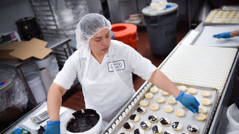   Laura Jaramillo  ices  the black-and-white  cookies  at Zaro's Family Bakery in the Bronx. 