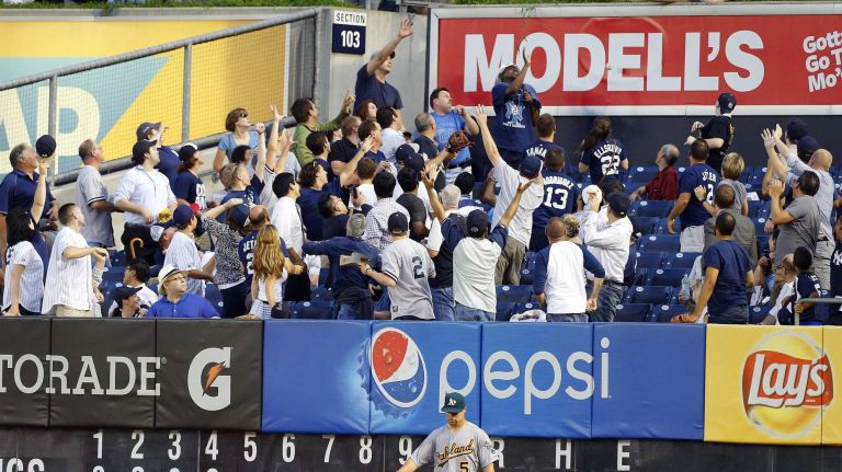 Fans reach for a home run ball hit by Mark Teixeira #25 of the New York Yankees in the fourth inning against the Oakland Athletics at Yankee Stadium on Wednesday, July 8, 2015. 