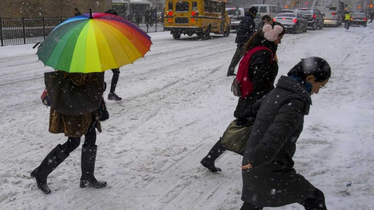 A rainbow umbrella brightens an otherwise gray scene as wind and snow hit Manhattan on Jan. 21, 2014.