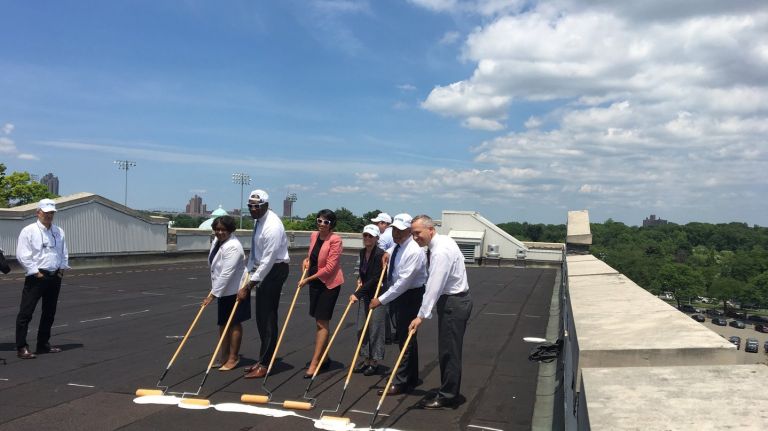 City officials help paint the roof of a Fordham University dorm white as part of a program to mitigate heat.