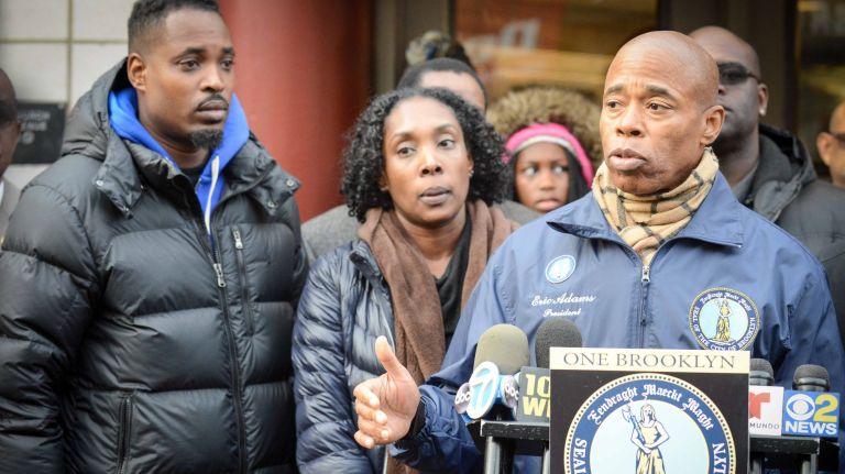 Borough President Eric Adams stands with Anthony Washington, left, and his sister Itisha, the children of Ann Marie Washington, outside the Church Avenue subway station in Flatbush. Their mother was allegedly assaulted in the station on Friday night and called a racial slur.