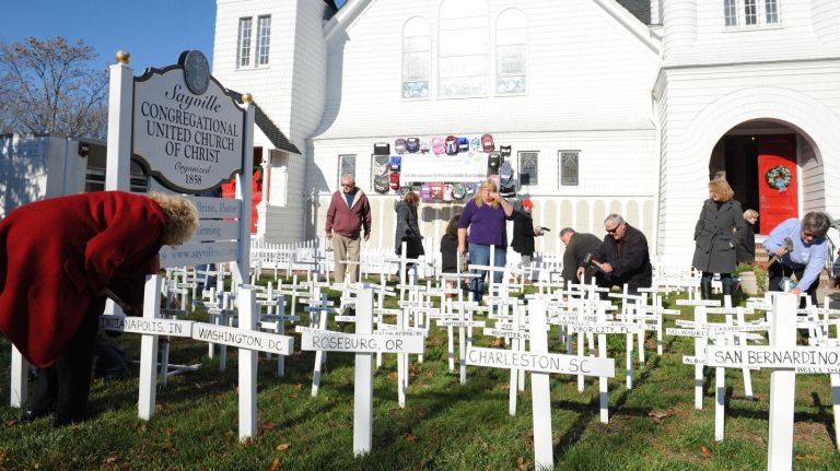 Parishioners at the Sayville Congregational United Church of Christ install hundreds of crosses in front of church on Sunday, Dec. 6, 2015 which reflects locations in the United States where mass casualty shootings occurred.