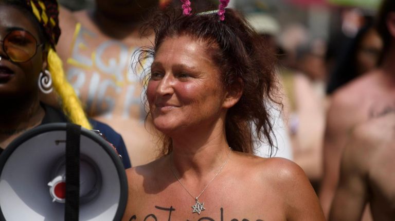 A woman goes topless down Broadway.
