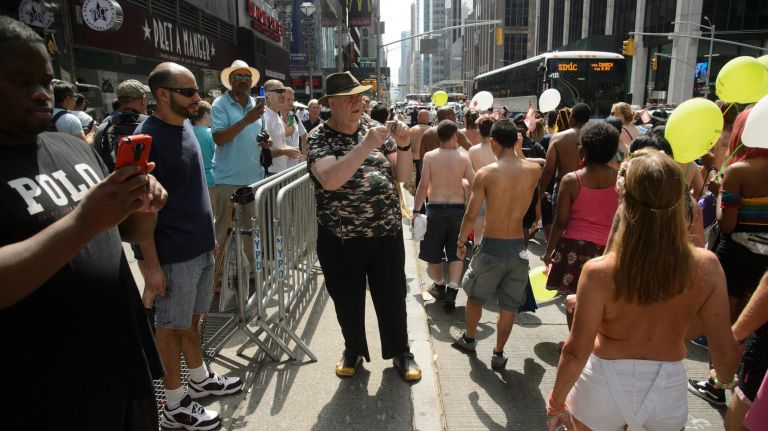 Spectators watch as topless participants march.