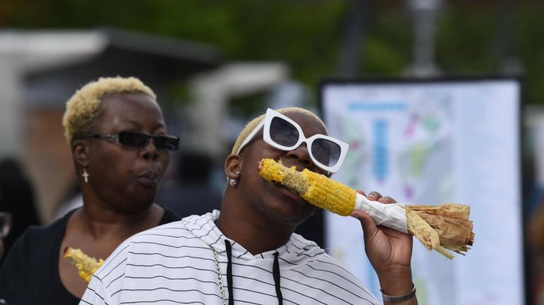 Keke Hoyte, enjoys her corn with her mom behind her, Pam Barnes of the Bronx at theThe Bronx Night Market. The market began its second season with a bang as thousands flocked to try the variety of food and drink at the Fordham Plaza site in the Bronx.