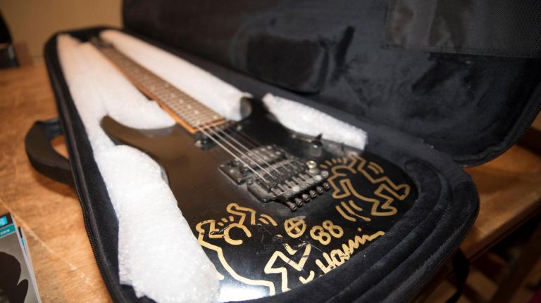Artist Keith Haring's signature and famous figures are on view on a black electric guitar.
