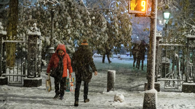 People cross the snow-coated street on Park Row near City Hall in Manhattan on Nov. 15, 2018.