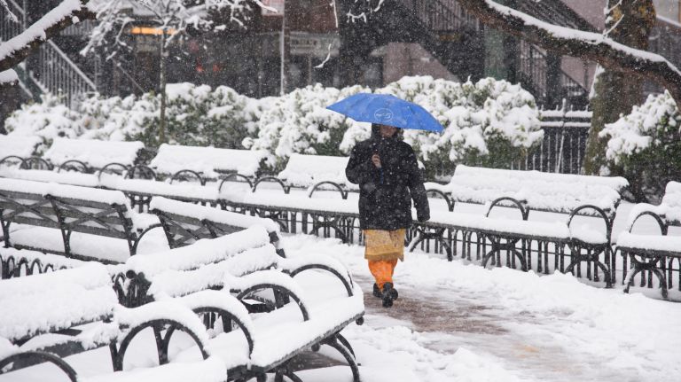 A woman walks through John Vincent Daniels Jr. Square as snow falls in Woodside, Queens, on April 2, 2018.