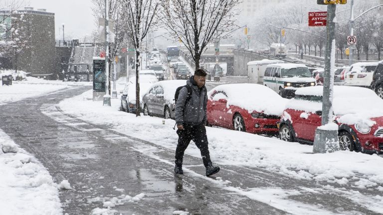 Pedestrians make their way through a snowfall on 161st street near Yankee Stadium in the Bronx on April 2, 2018.