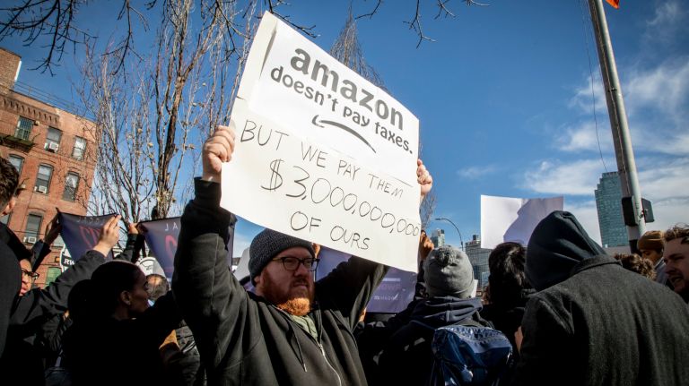 Sam Meyers, 43, of Long Island City, holds a sign at a rally Wednesday&nbsp;criticizing the tax incentives promised to Amazon in a deal to bring one of its new headquarters to Queens.&nbsp;