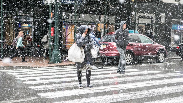 Pedestrians quickly cross the street as the snow begins to build early afternoon near Grand Central Terminal in Manhattan on March 21, 2018.