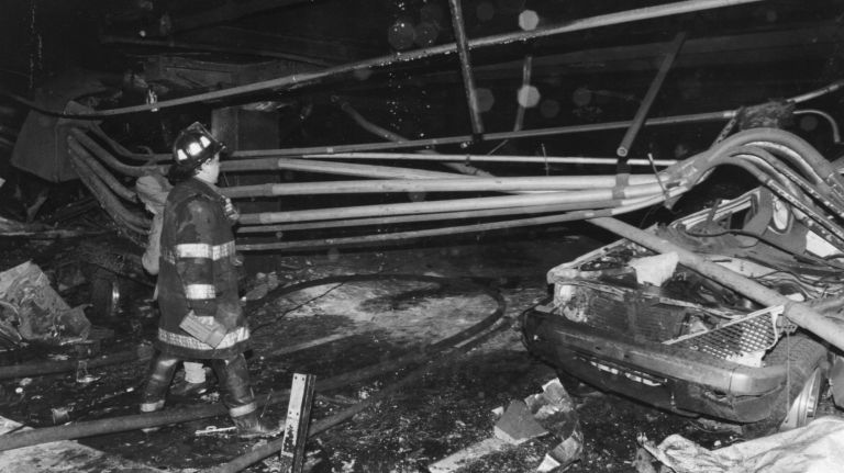 A firefighter walks past a car destroyed by the explosion in the underground parking garage of the World Trade Center's north tower on Feb. 26, 1993.