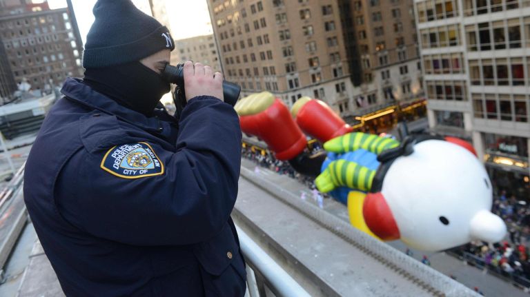 Cop keeps eye on the crowd as loats, balloons, bands and clowns march on Sixth Avenue during the Macy's Thanksgiving Parade on Thursday.