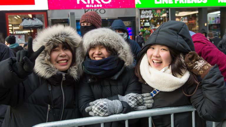Kyoka Yamanaka, Miori Rue, and Kaho Maeda, all 20, wait inside one of the pens in Times Square before the New Year's Eve celebration on Sunday, Dec. 31, 2017.