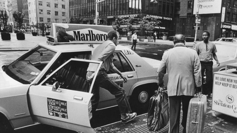 NYC in the 1980s: See pictures of big moments and everyday life 30 A taxi driver parked in front of the Sheraton New York Times Square Hotel on Seventh Avenue and 53rd Street as a doorman brings luggage to the curb on July 7, 1984.