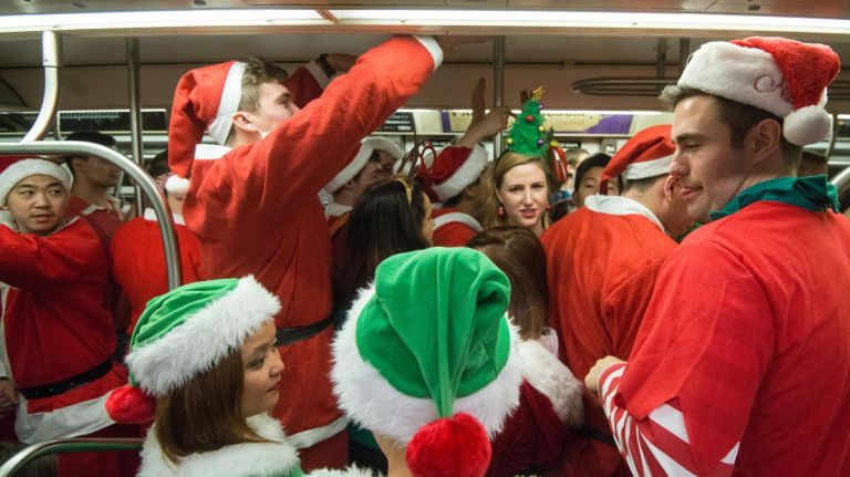 Santas board a crowded subway train.