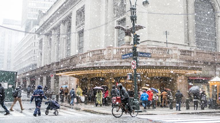 People quickly cross the street as the snow begins to build near Grand Central Terminal in Manhattan on March 21, 2018.