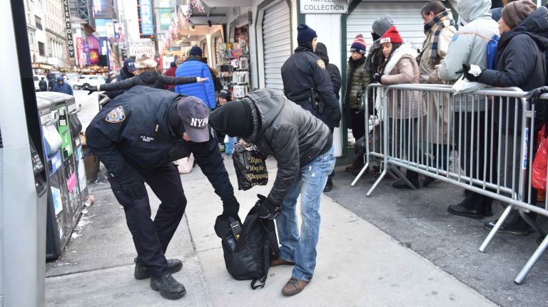 Cops search a bag as New Year's Eve revelers get ready to celebrate in a frigid Times Square on Sunday, Dec. 31, 2017.