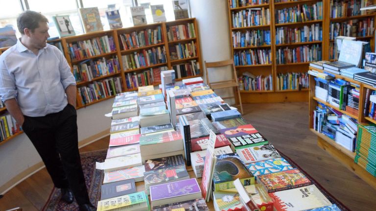 A person peruses a long table of books inside Idlewild.