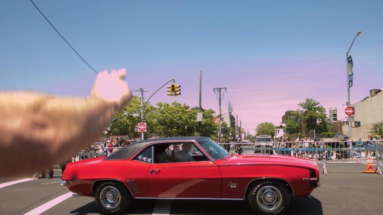 A reveler salutes as a classic car passes during the Coney Island Mermaid Parade.