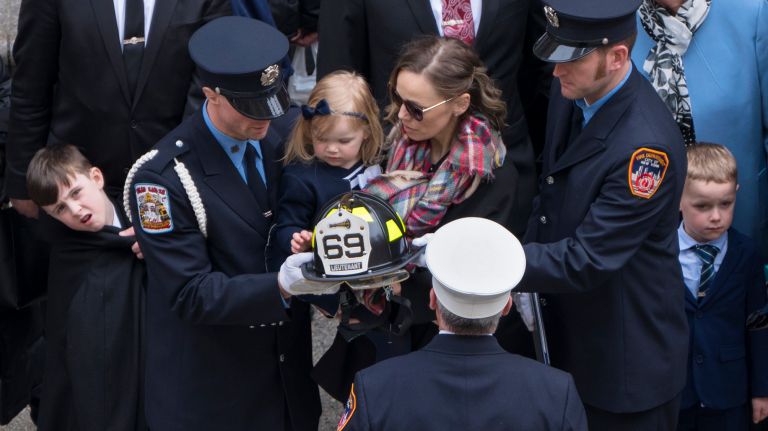 Eileen Davidson, wife of FDNY firefighter Michael Davidson, holds a helmet given to her family after her husband's funeral at St. Patrick's Cathedral on Tuesday.